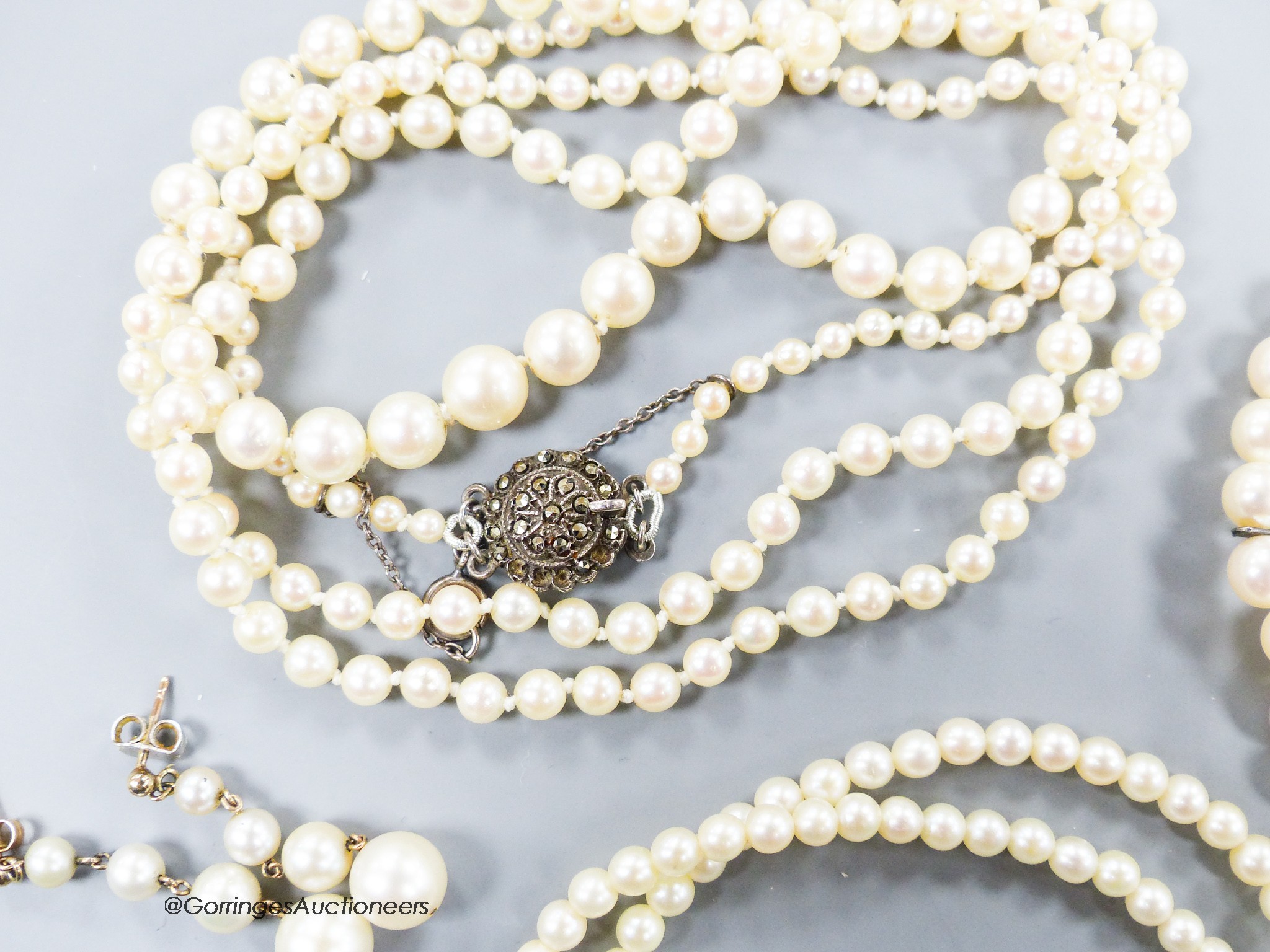 A long single strand graduated cultured pearl necklace, with marcasite clasp, 90cm, one other similar smaller necklace, a similar double strand bracelet and a pair of earrings(a.f.).